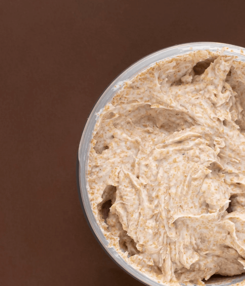 Vue du dessus de l’exfoliant corporel O’terra avec texture granuleuse douce et décor botanique.