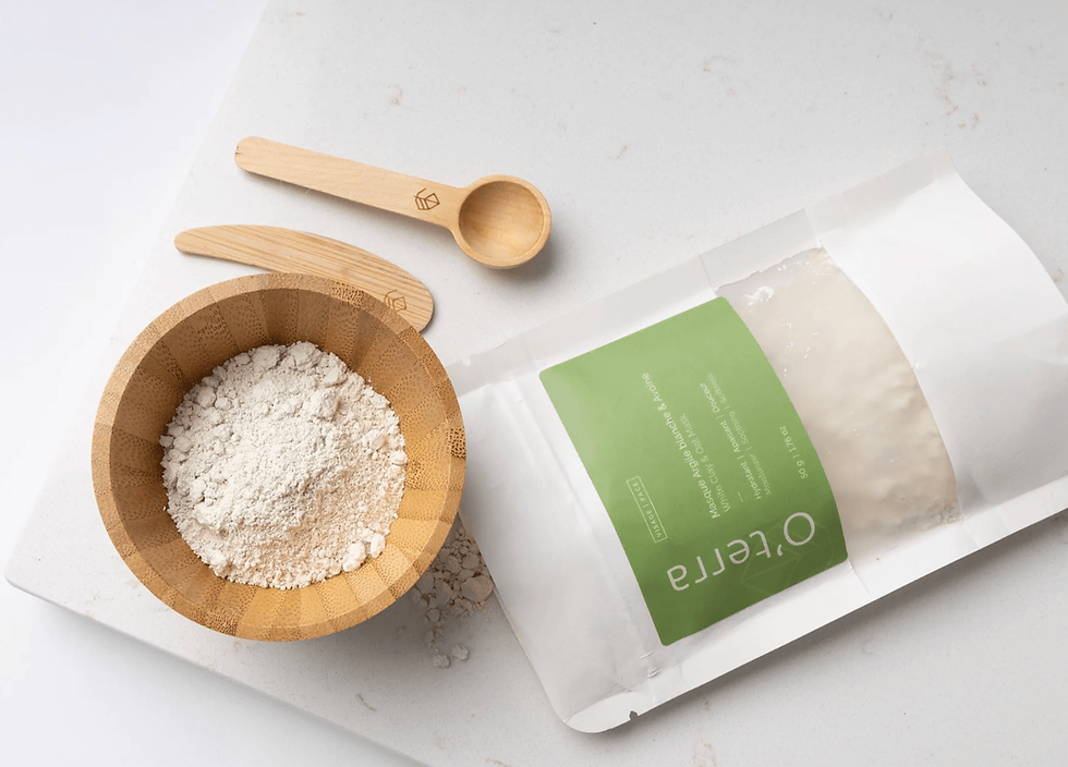 Poudre de masque à l’argile blanche O’terra dans un bol en bois avec accessoires de soin naturels.