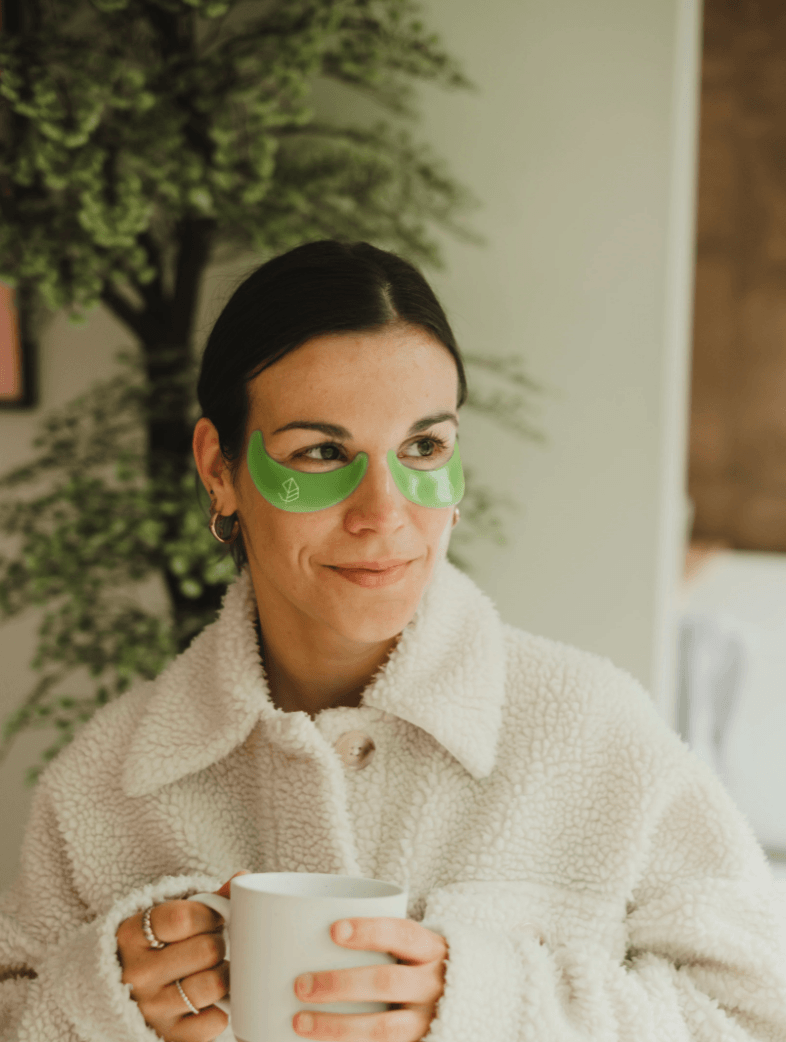 Femme relaxant dans un bain avec des patchs pour les yeux O’terra verts appliqués sous les yeux.