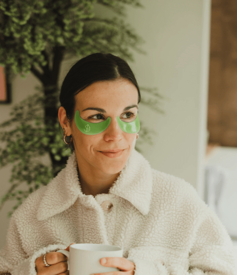 Femme relaxant dans un bain avec des patchs pour les yeux O’terra verts appliqués sous les yeux.