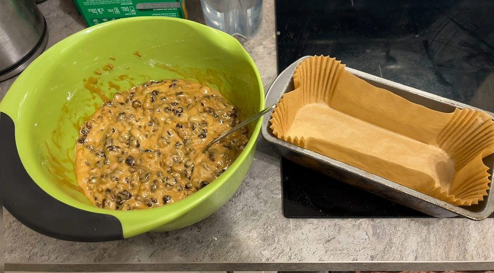 Cake batter in a green bowl and a lined loaf tin.