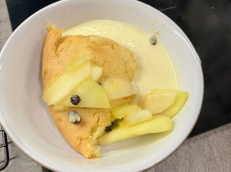 A serving of Eve's pudding with custard.