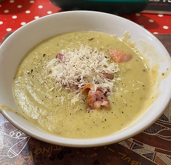A bowl of leek and potato soup with bacon and cheese on top.