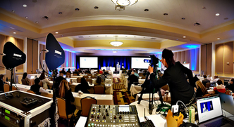 View from professional AV booth live streaming and recording corporate meeting presentation on stage with speaker