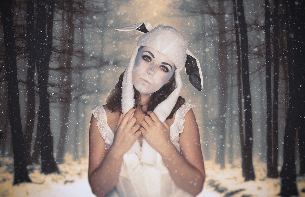 Woman in white hat with ears in snowy forest