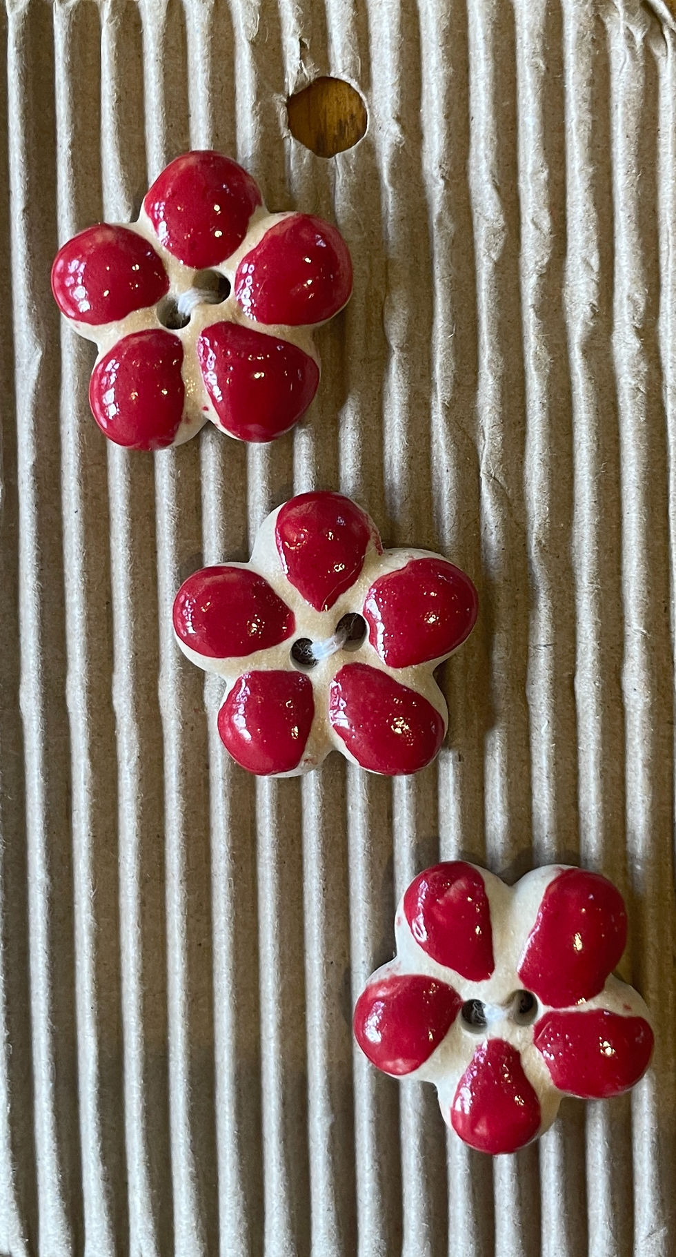 Hand-painted red ceramic flower buttons on display card