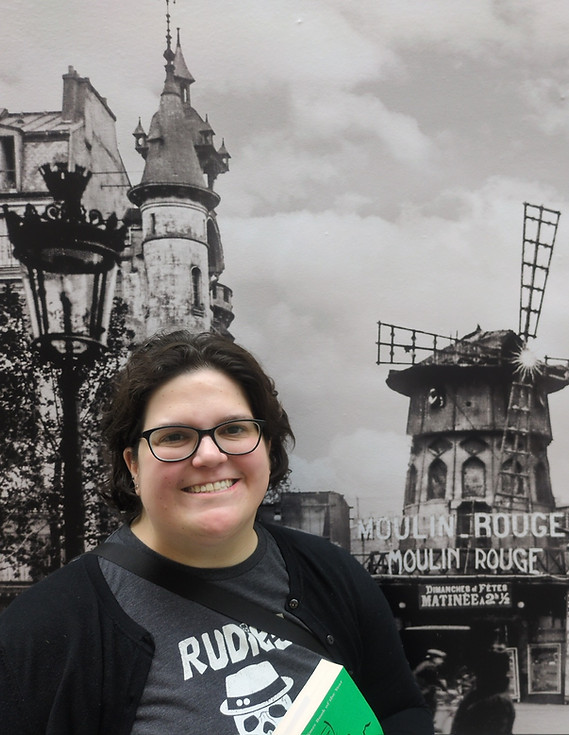 jahnna at the speed art museum for an exhibit poses in front of a mural of paris