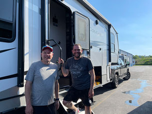 Jon and Rich standing with their truck and fifth wheel RV after purchasing it to begin full-time RV life