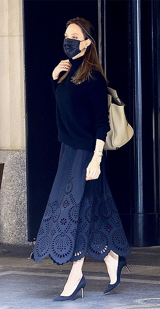 Angelina Jolie veste look monocromático de sueter e saia midi azul marinho com scarpin azul marinho.
