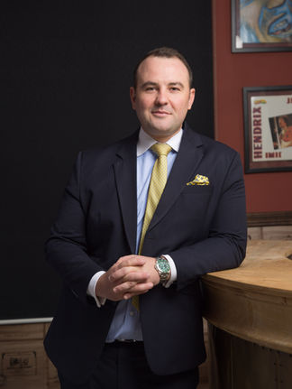 Portrait of a businessman posing in his smart suit within his home office, blending professional attire with a comfortable, personal workspace. This image captures the modern trend of working from home, showcasing his polished look in a more relaxed setting. Ideal for articles about remote work, professional networking sites, and personal branding, it highlights the balance between business professionalism and the intimacy of a home environment