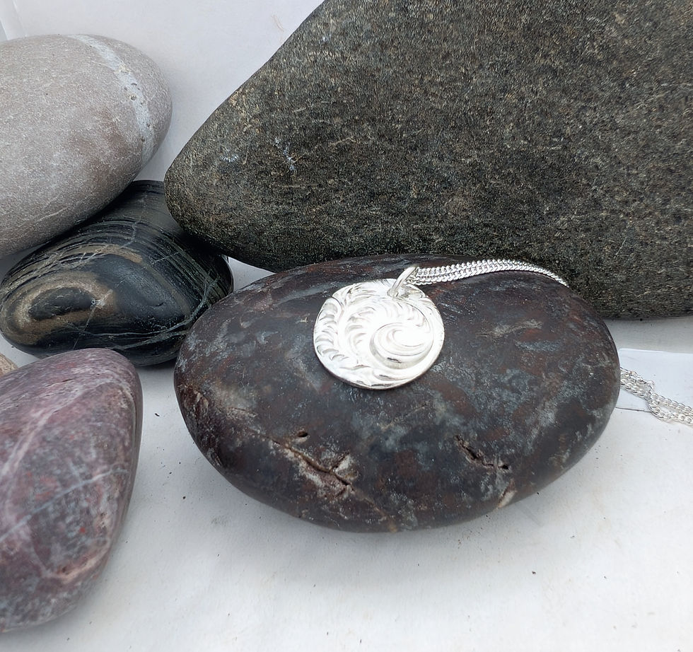 Thumbnail: Round silver fern necklace on a pebble