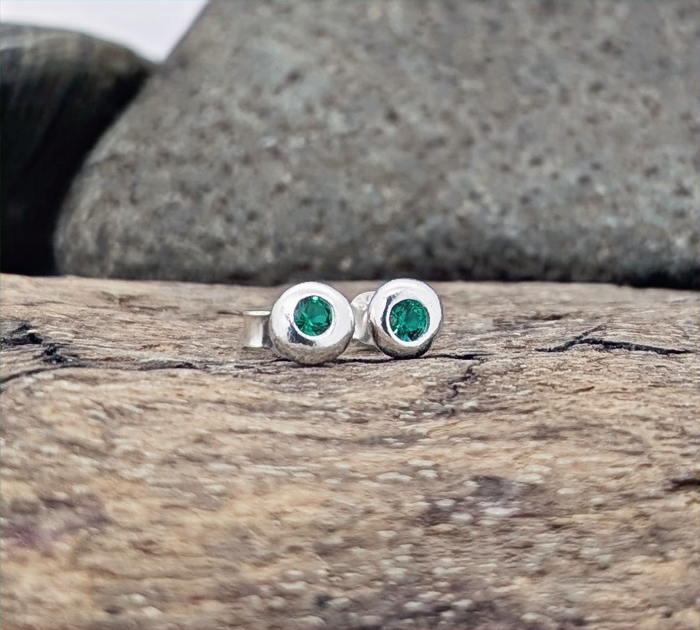 Emerald green and silver berry bead stud earrings on a log