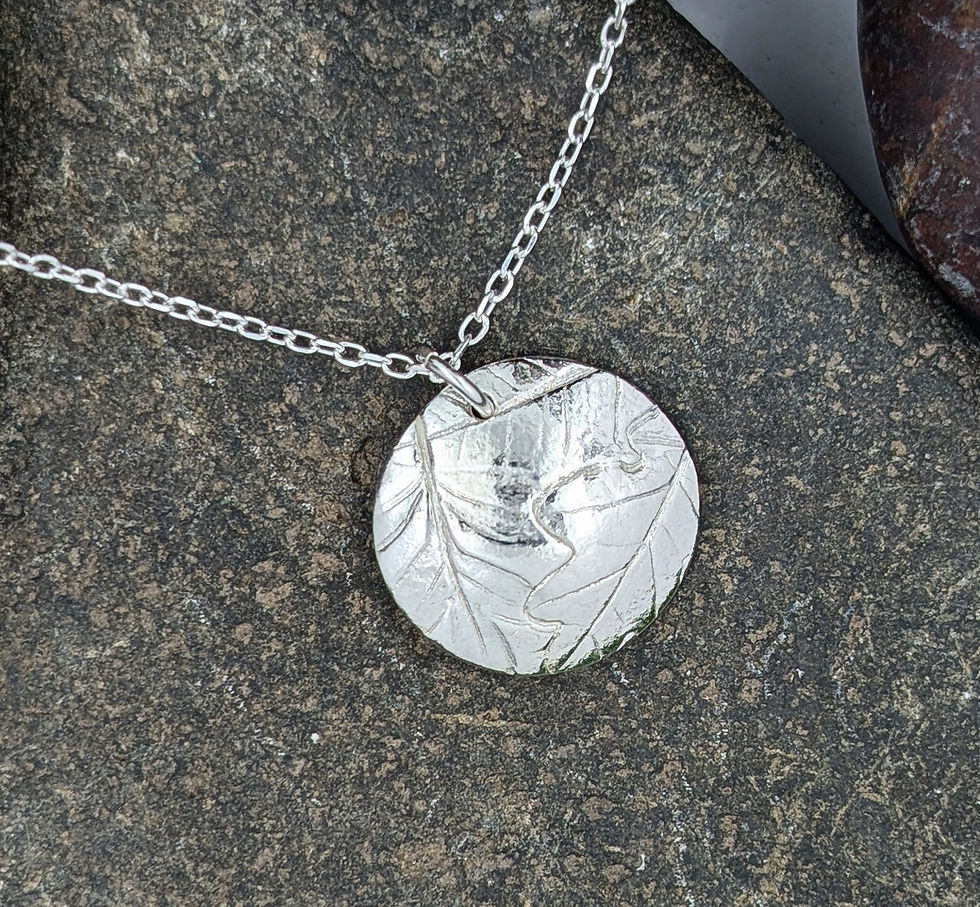 silver leaf circle necklace on a pebble