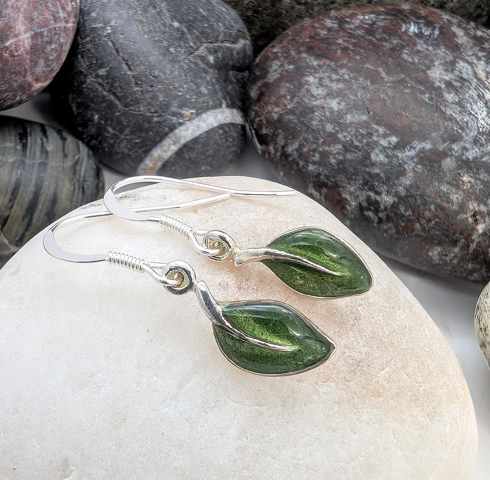 Emerald green leaf earrings on a pebble close up