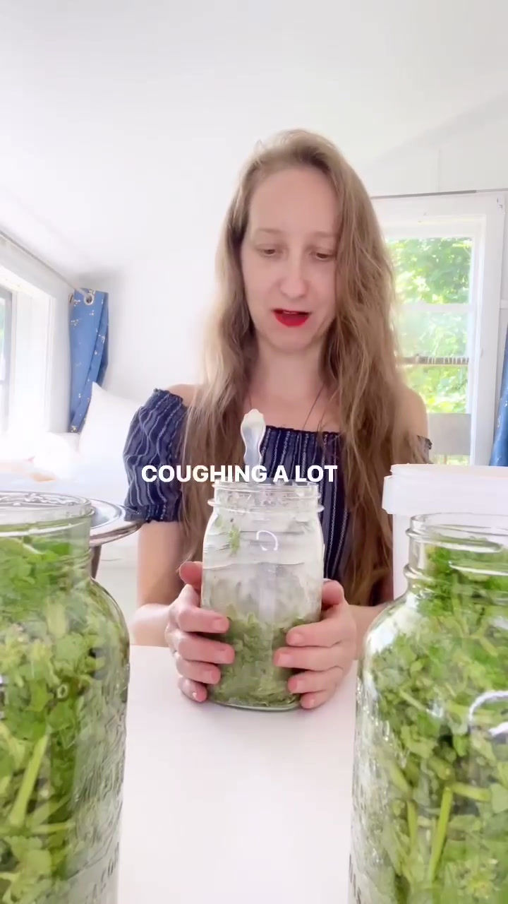 A woman in a navy blue dress sitting at a white desk covered in Horehound and mason jars.