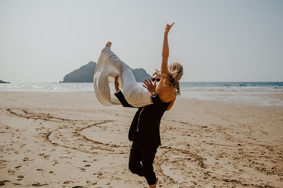 A wedding couple celebrating on the beach. groom is throwing bride into the air.