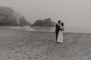 Wedding couple embrace on misty Cornish beach