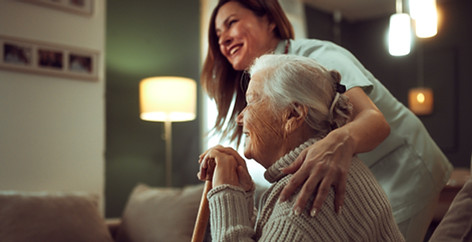 Personne âgée assise avec une canne, avec un physiothérapeute à domicile de Physio à la Maison.