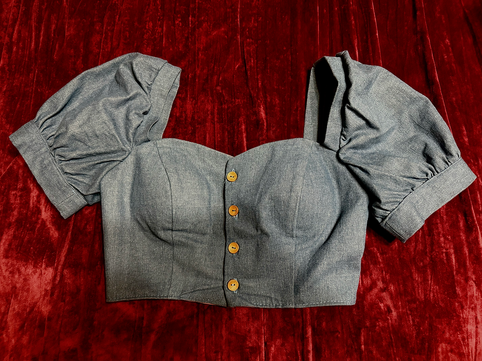 A fitted blouse with puffy sleeves and wooden buttons against a red velvet background. The fabric is wrinkled and worn.