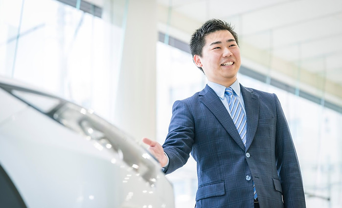 スーツ姿の男性社員が車の説明をしている様子