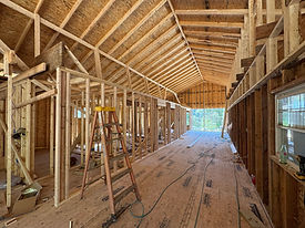 Wide view of wall framing beneath exposed roof rafters.