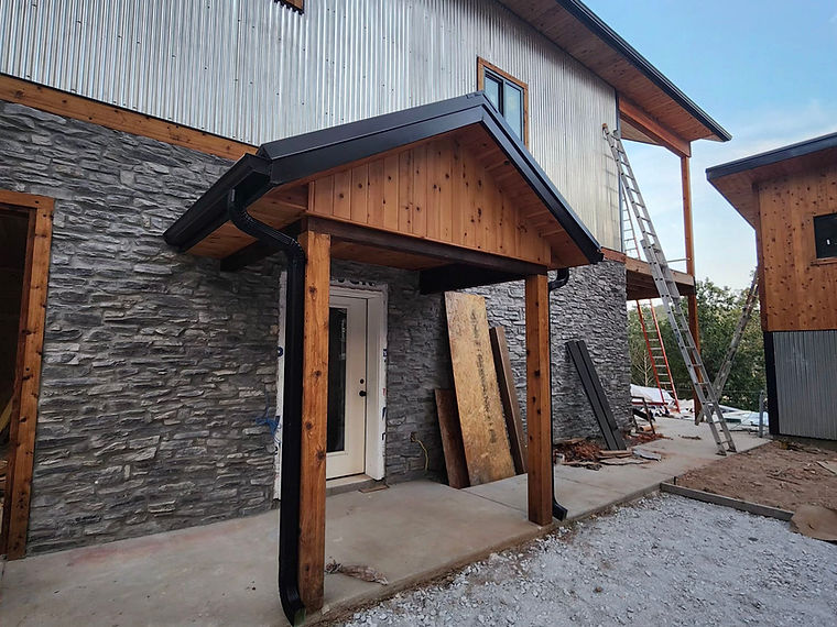 Timber entrance canopy beside textured gray exterior cladding.