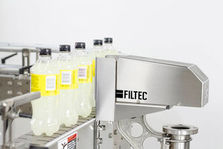 Product photo of bottle inspection equipment in action with several yellow labeled clear bottles on white background