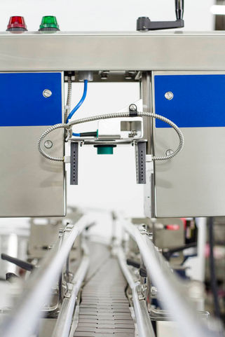 Product photo of bottle inspection equipment in action on white background