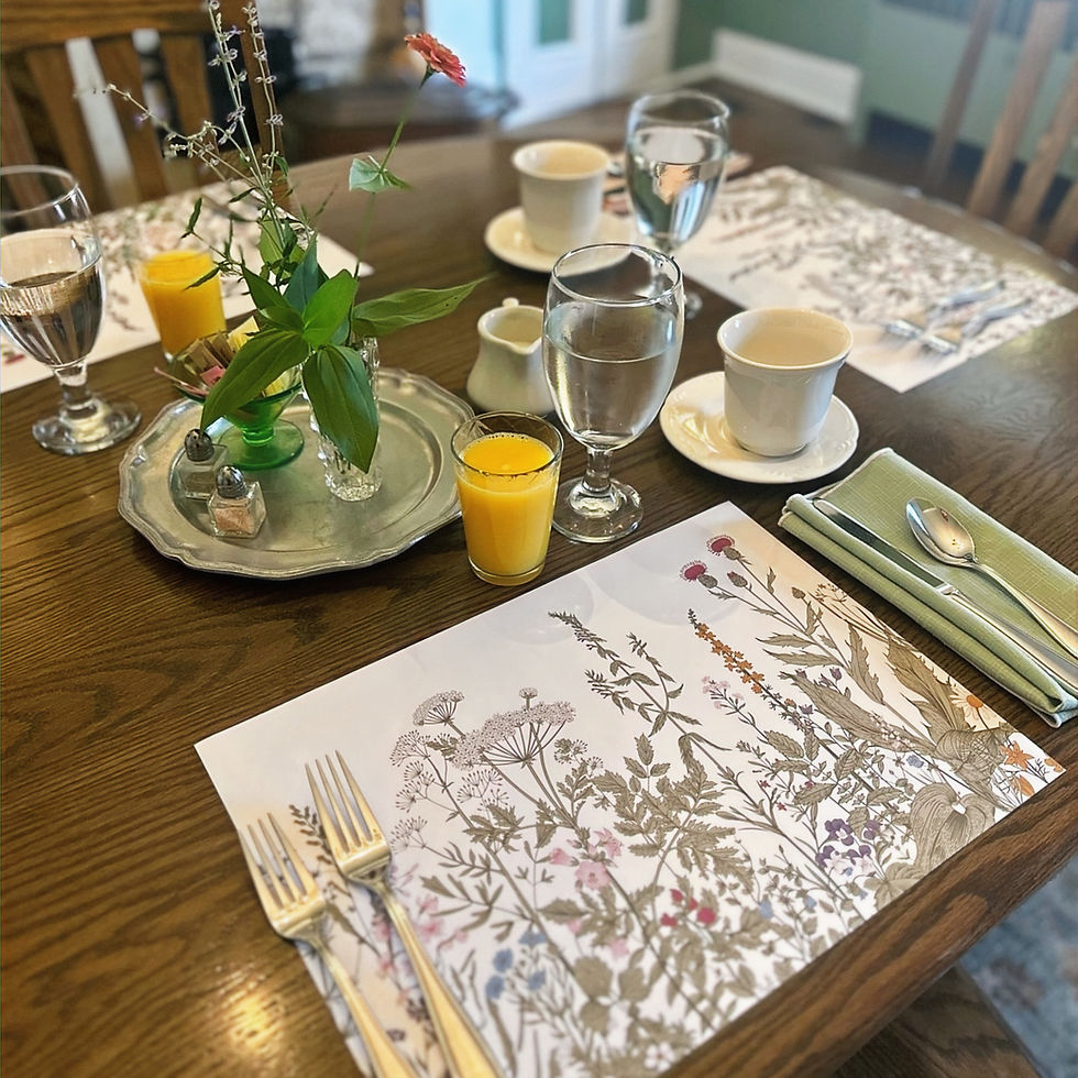 A thoughtfully set breakfast table at The Inns at 8th & Main with fresh flowers, coffee cups, orange juice, and place settings in a calm dining room.
