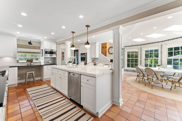 Transitional kitchen with white shaker style cabinets, quartz island overlooking swimming pool