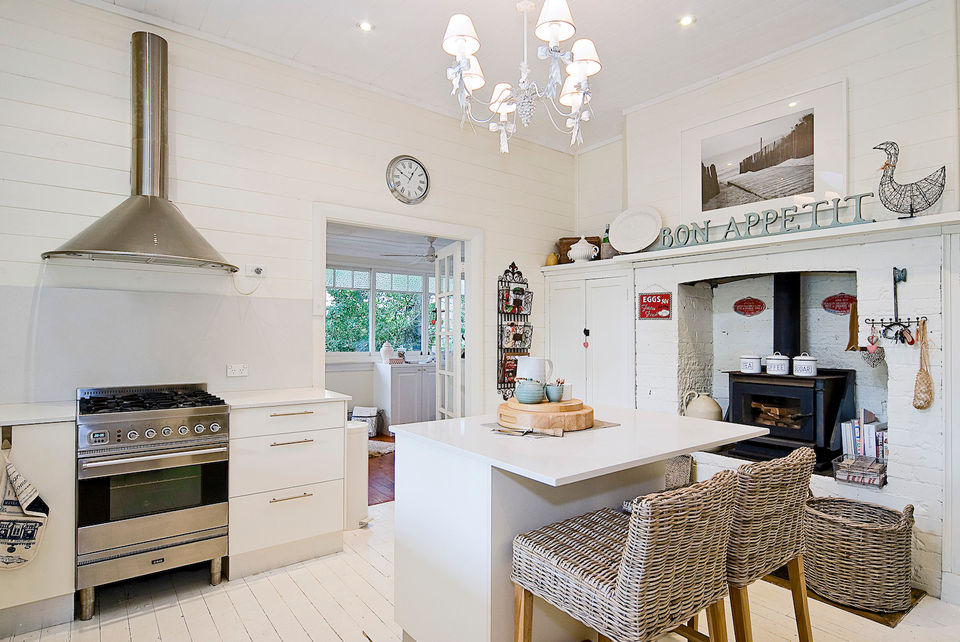 quintessential Australian beach house kitchen with rattan stools, whitewashed floorboards and french country chandelier