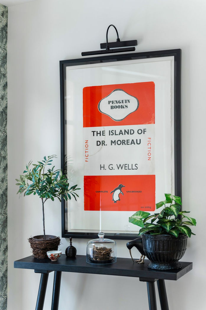 Black framed Penguin book art  above black console table