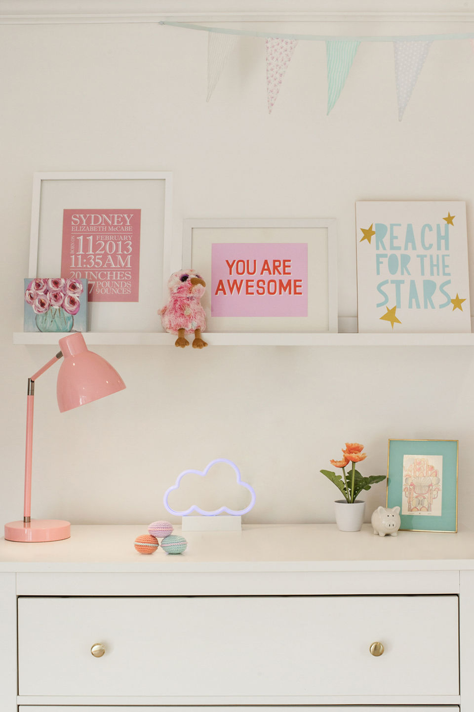 Girls bedroom chest of drawers with artwork and pink lamp