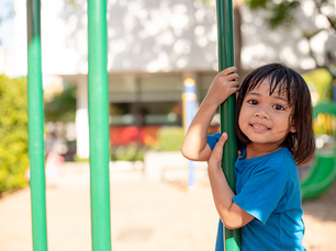 Niña en área de juegos infantiles sonriendo a la cámara, imagen que ilustra el impacto del acceso al cuido infantil en el desarrollo de la niñez en Puerto Rico.