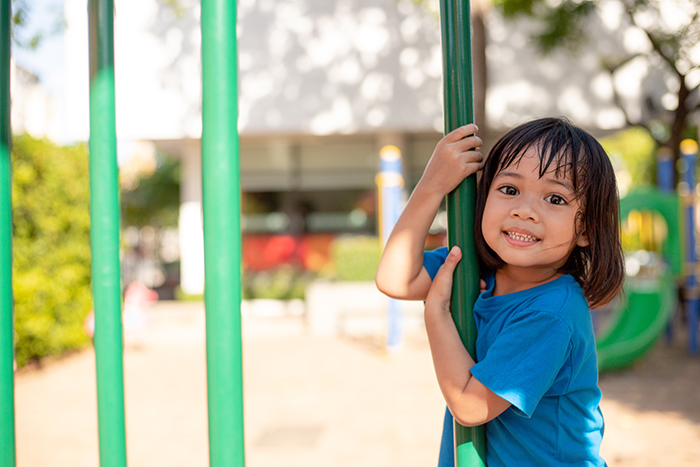 Niña en área de juegos infantiles sonriendo a la cámara, imagen que ilustra el impacto del acceso al cuido infantil en el desarrollo de la niñez en Puerto Rico.