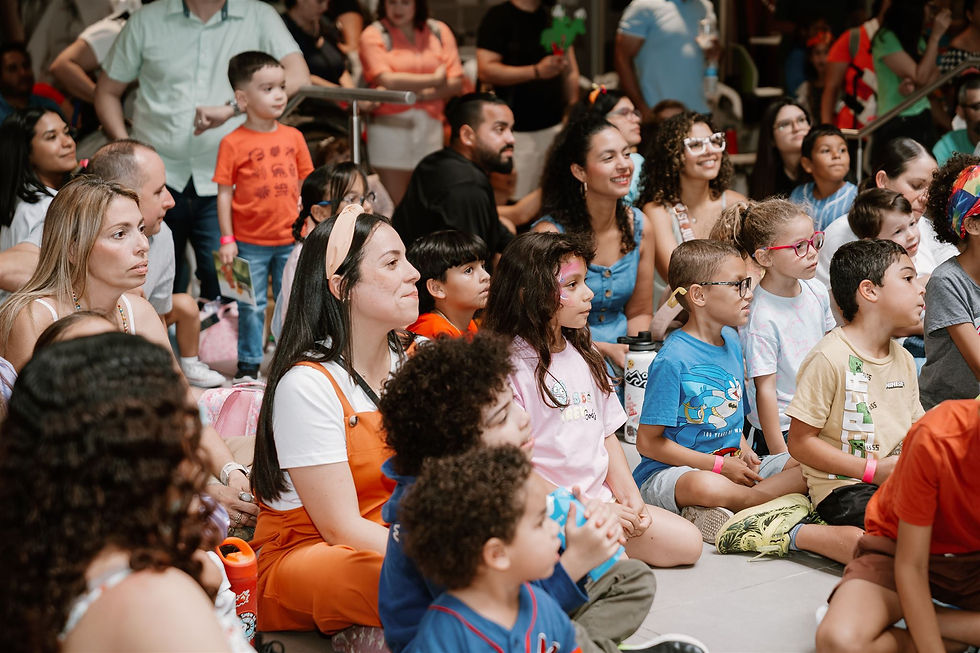 Decenas de niñas, niños y familiares sentados en el piso disfrutan de una presentación durante la tercera edición del Lectura Fest, con rostros atentos y algunos con pintura en sus caritas.