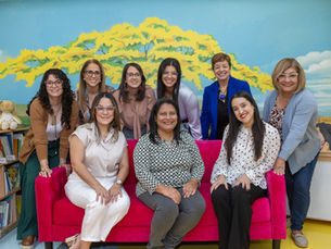 El equipo de coordinadoras de la Iniciativa Preescolar de la Fundación Ángel Ramos posa en una sala de lectura infantil decorada con un mural de árbol amarillo, ante el Día de la Iniciativa Preescolar 2026 en Mayagüez.