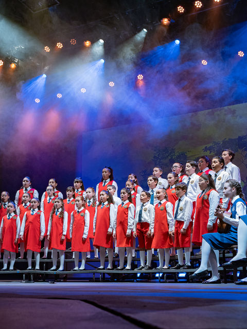 Coro de Niños de San Juan canta en el escenario durante el concierto “60 años en voz”, bajo la dirección de su directora musical.