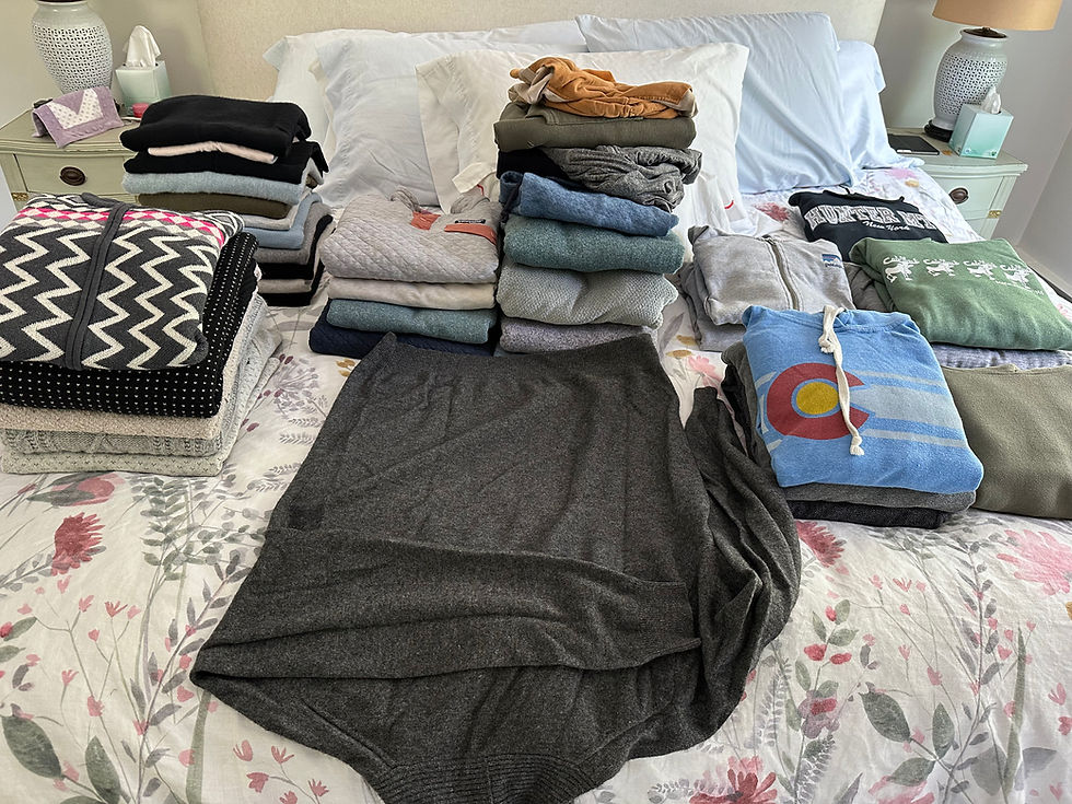 Stacks of sweaters and hoodies on a bed