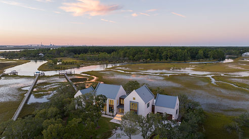 beautiful home with standing seam metal roof tucked into nature and a sunset