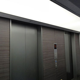 窓のないエレベーターホールに自然光を取り入れる。屋上の他の設備による太陽光の遮蔽を避けるため、立ち上げたトップライトより採光。垂直型の光ダクトで導光して、エレベーターホールで広い範囲に光を照射できるように放光部を広げて設置している。