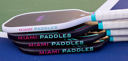 Stack of Miami Paddles pickleball paddles showcasing various custom designs.