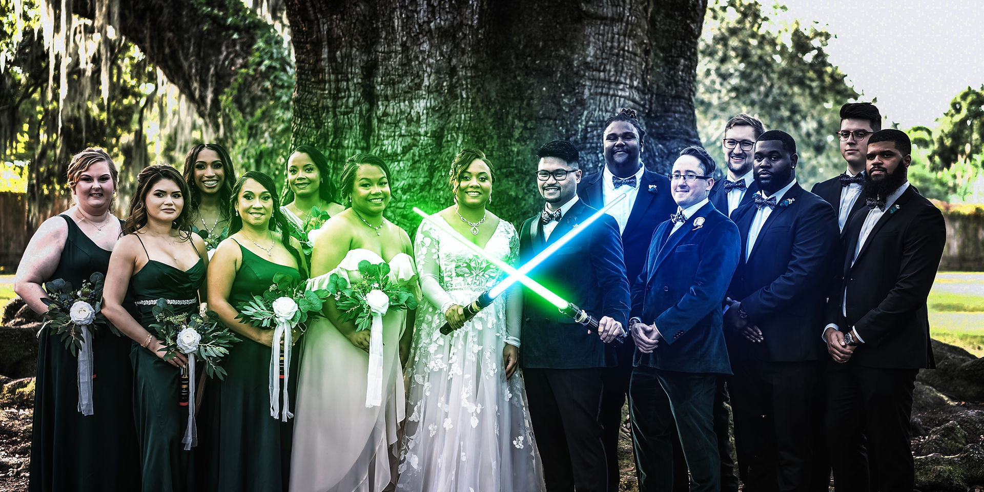 Close-up of the couple’s hands gripping lightsabers, rings visible, tree canopy and party guests blurred in the background.