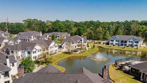 Low aerial view of apartment complex roof and landscaped water feature