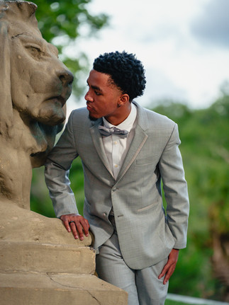 Confident young man posing for prom portraits in front of a City Park statue