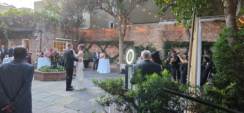 Scarlett and Brennan sharing their first dance at Broussard's wedding reception with the iPad photo booth and cream backdrop in the background.