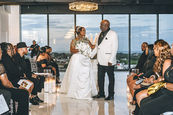 Evangeline and Michael walking down the aisle as newlyweds at NOLA Skyline Event Center in mixed warm indoor light and twilight