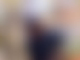 Young man holding a camera gimbal, looking down. Elegant floral decor in the background, with bright lights and ornate mirrors.