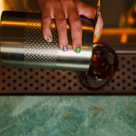bartender pouring cocktail into glass