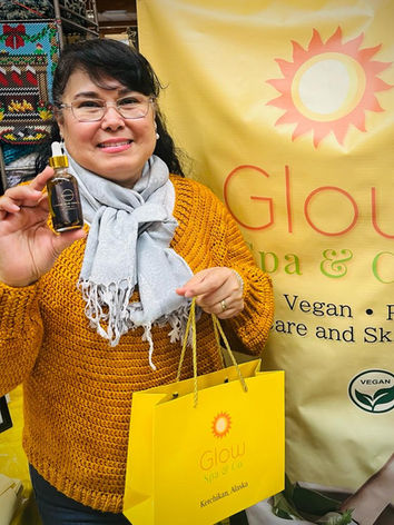 A woman holding Extreme Hair Growth Oil in front of the Glow Spa Sign